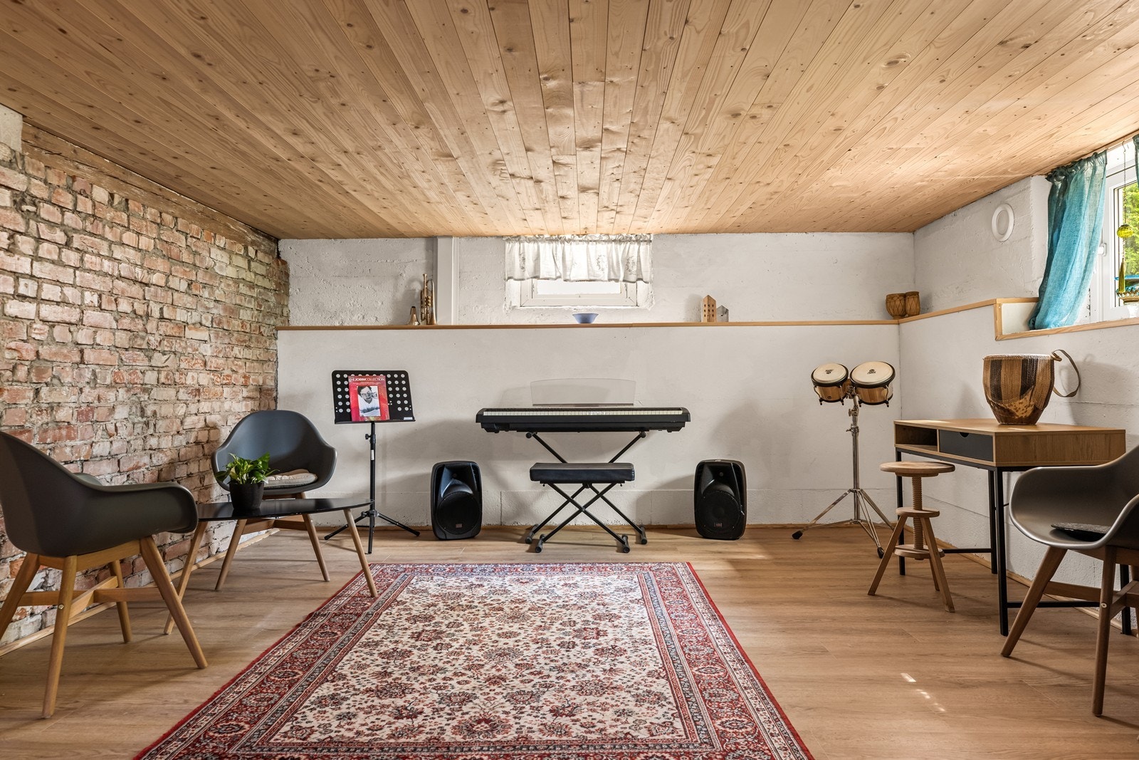 Innredet kjellerstue med eksponerte teglsteinsvegger og vedovn. Galleribilde