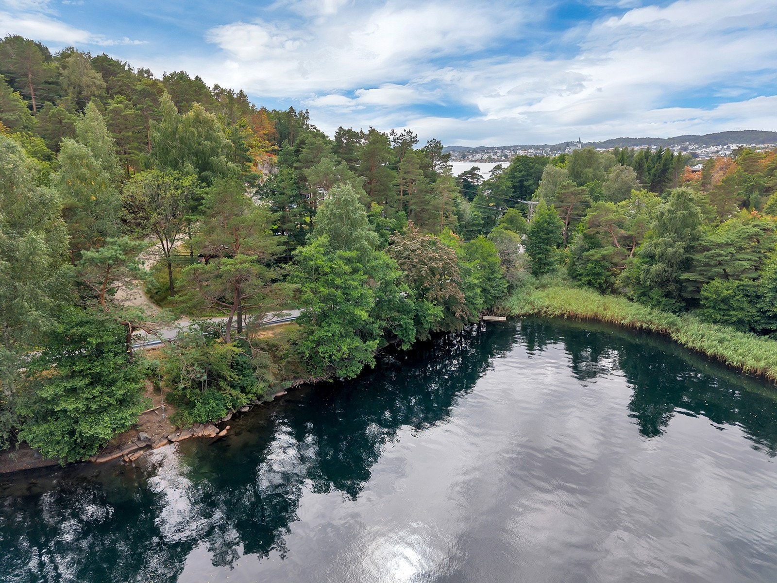 Her ser man veien opp til huset mellom buskene. Badeplassen ligger like på andre siden av veien. Galleribilde