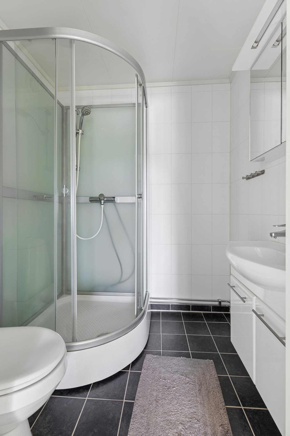 Badet har flislagt gulv og baderomsplater på veggene. Galleribilde