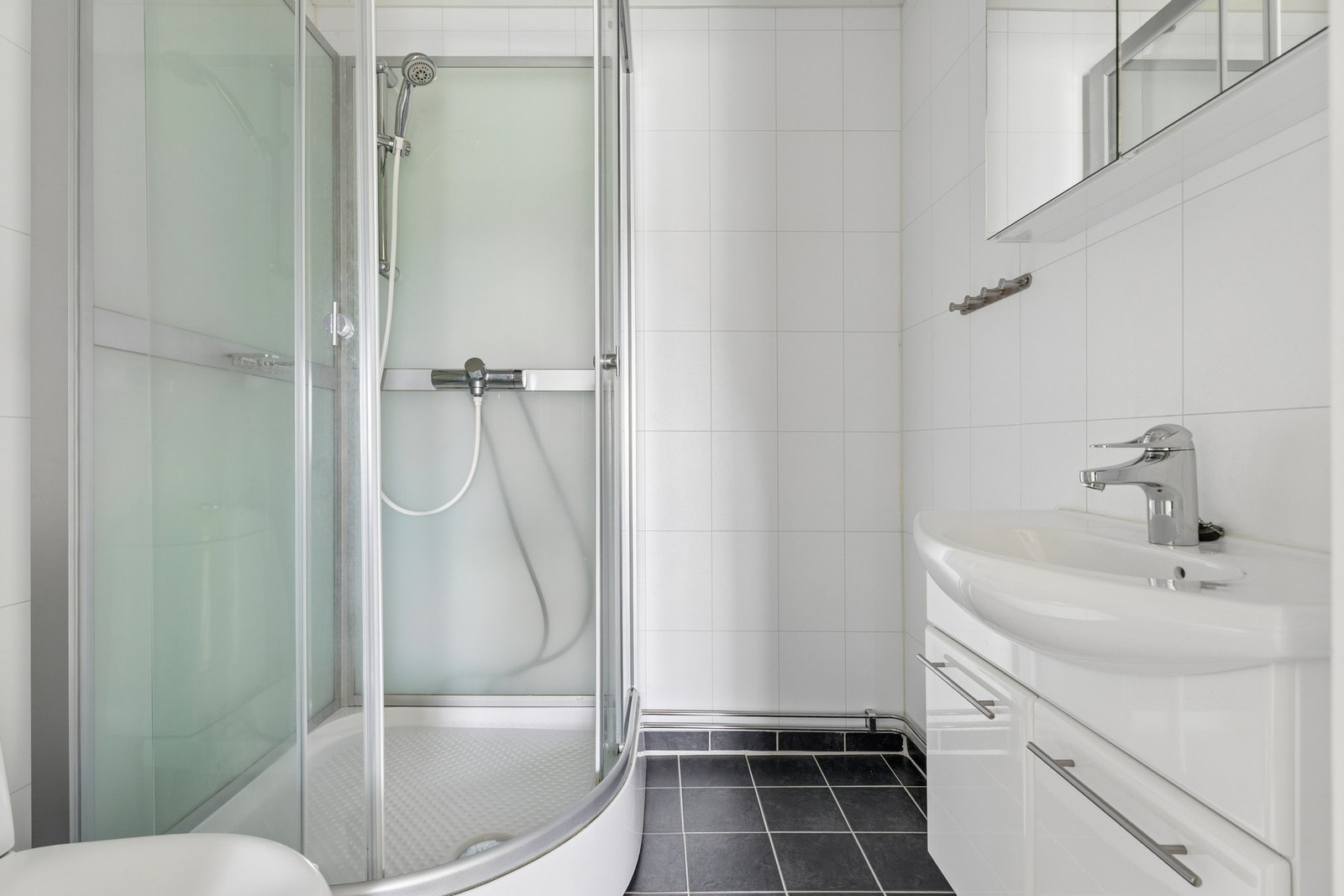 Badet er utstyrt med servant med underskap, toalett og dusjkabinett. Galleribilde