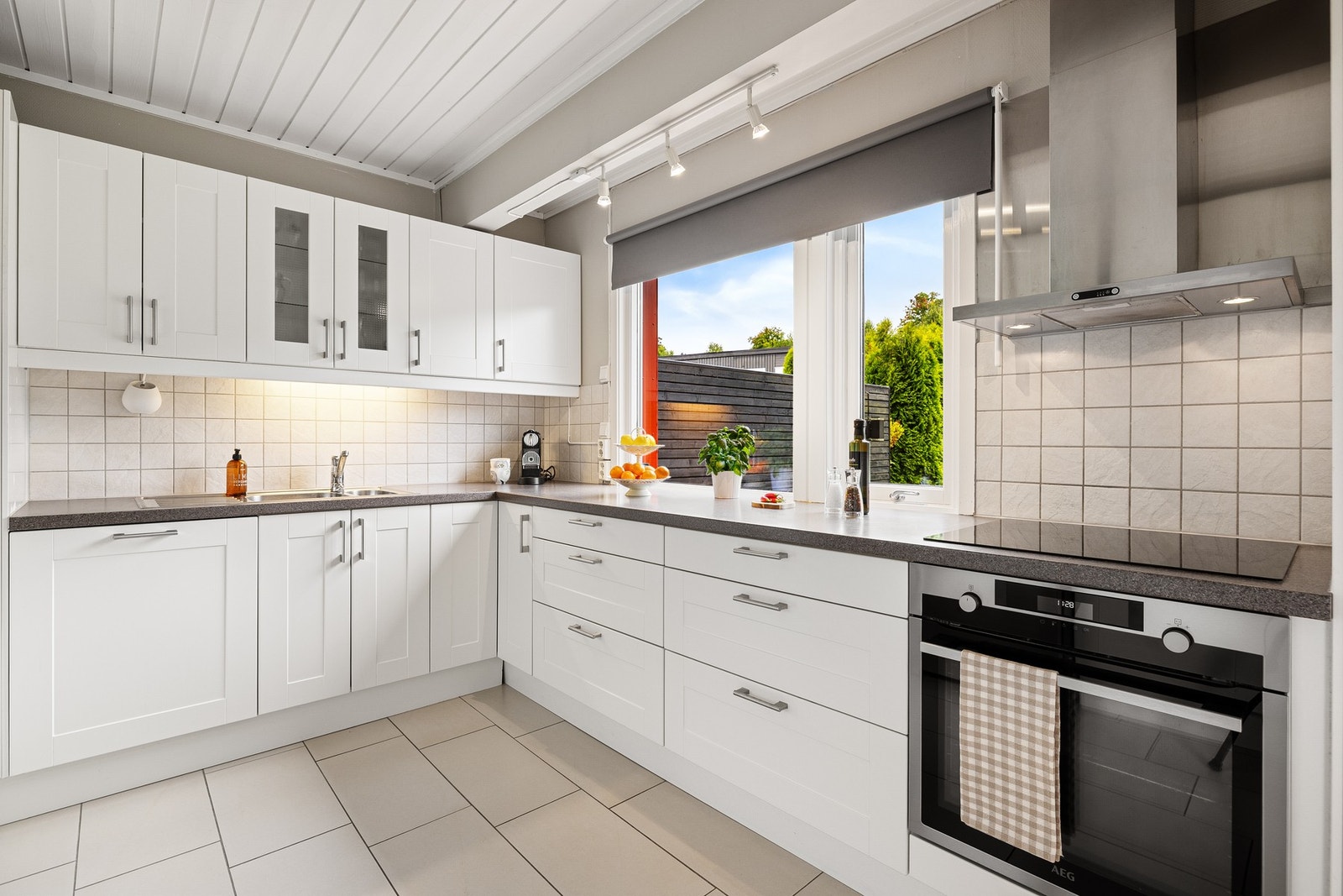 Kjøkkeninnredning med profilerte fronter og laminerte benkeplater. Ventilator over komfyr og platetopp. Galleribilde