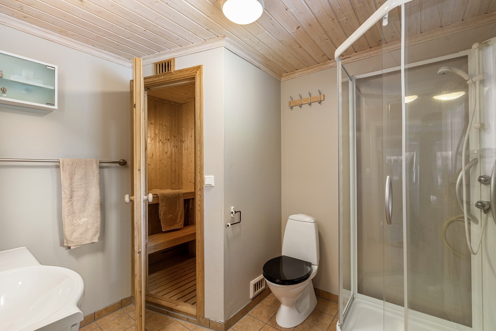 Badet har flislagt gulv, dusjkabinett og elektrisk avtrekksvifte. Galleribilde
