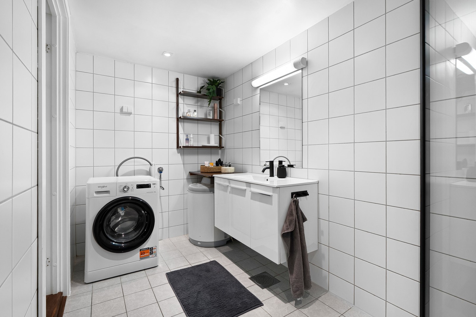 Romslig bad fra 2006. Innredningen består av en servantseksjon med skap, vegghengt toalett, dusjhjørne og speil. Opplegg for vaskemaskin. Galleribilde
