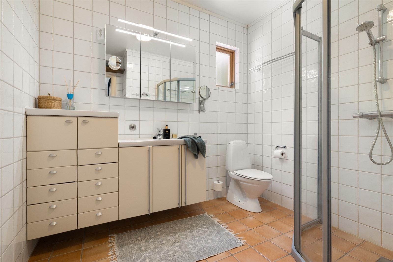 Badet i hovedetasjen er helfliset og innredet med dusj med skyvedør, toalett og servant med møblement. Det er varmekabler i gulvet. Galleribilde