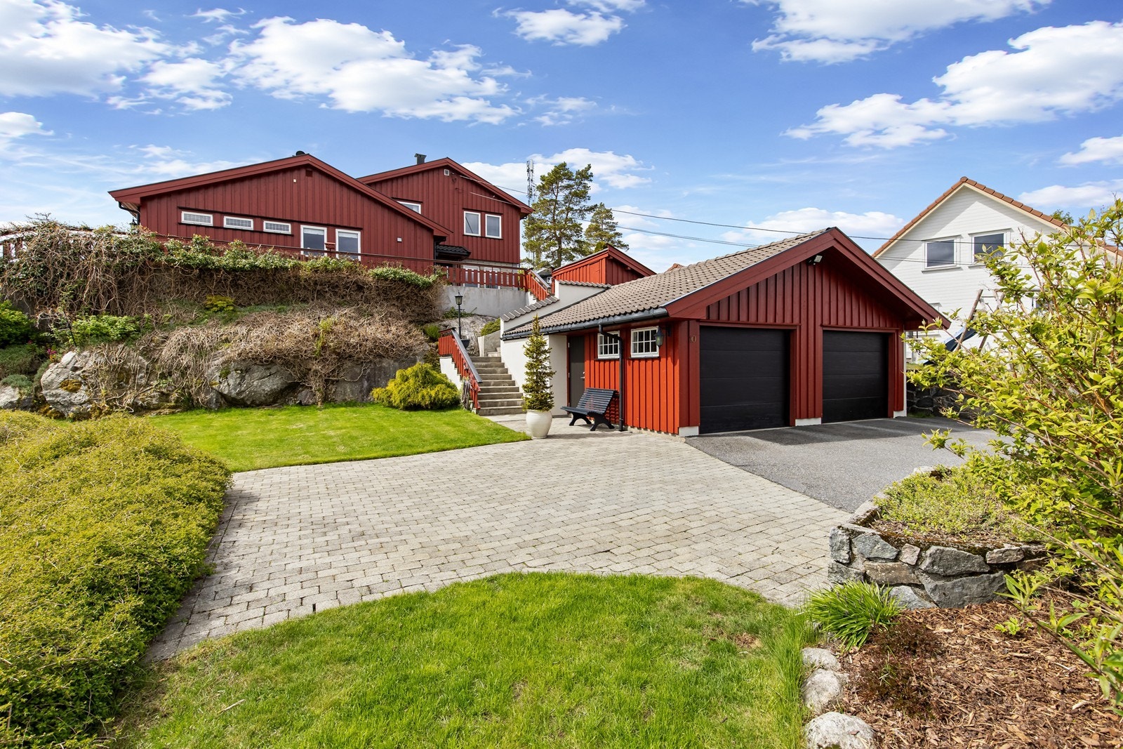 Tomten er pent opparbeidet med belegningsstein, bed, noe naturtomt og plen Galleribilde
