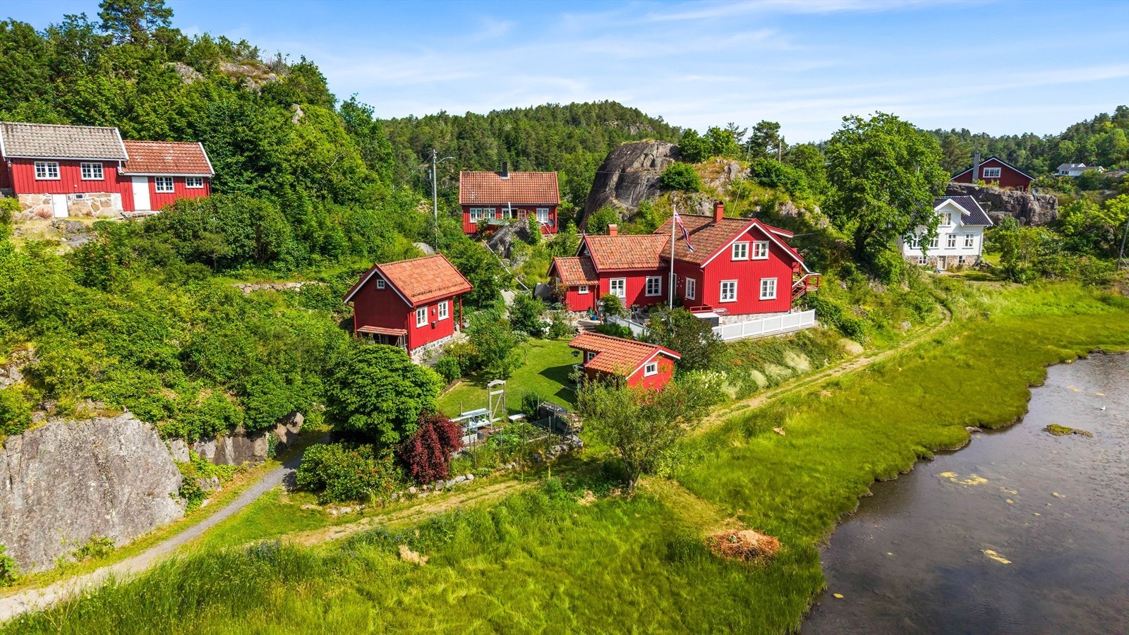 Oversikt over eiendommen med hovedhus og to uthus/boder. Galleribilde