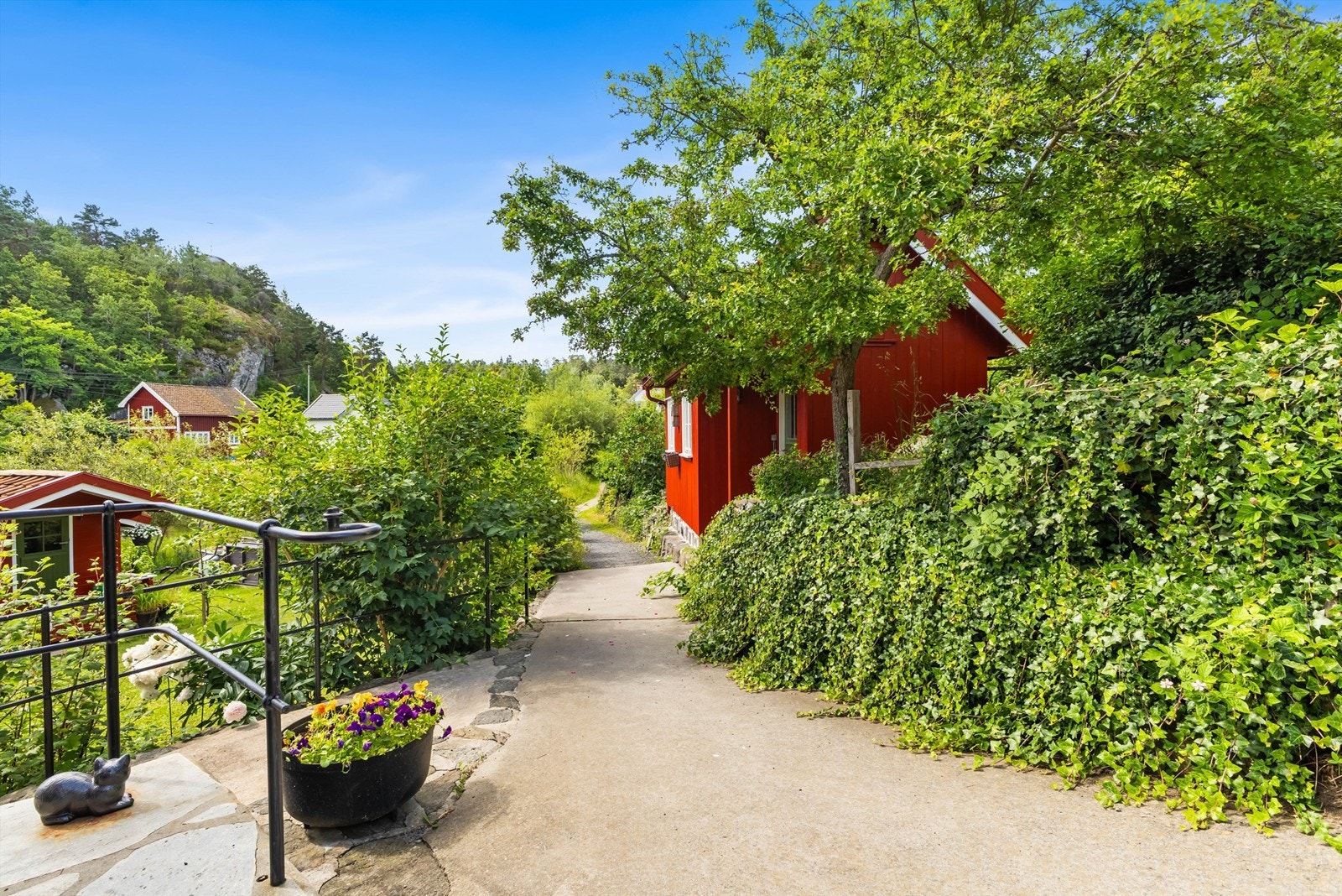 Gangstien fører gjennom den frodige og veletablerte hagen. Det er offentlig sti forbi huset og videre utover til Kalvenbrua bl.a. Galleribilde