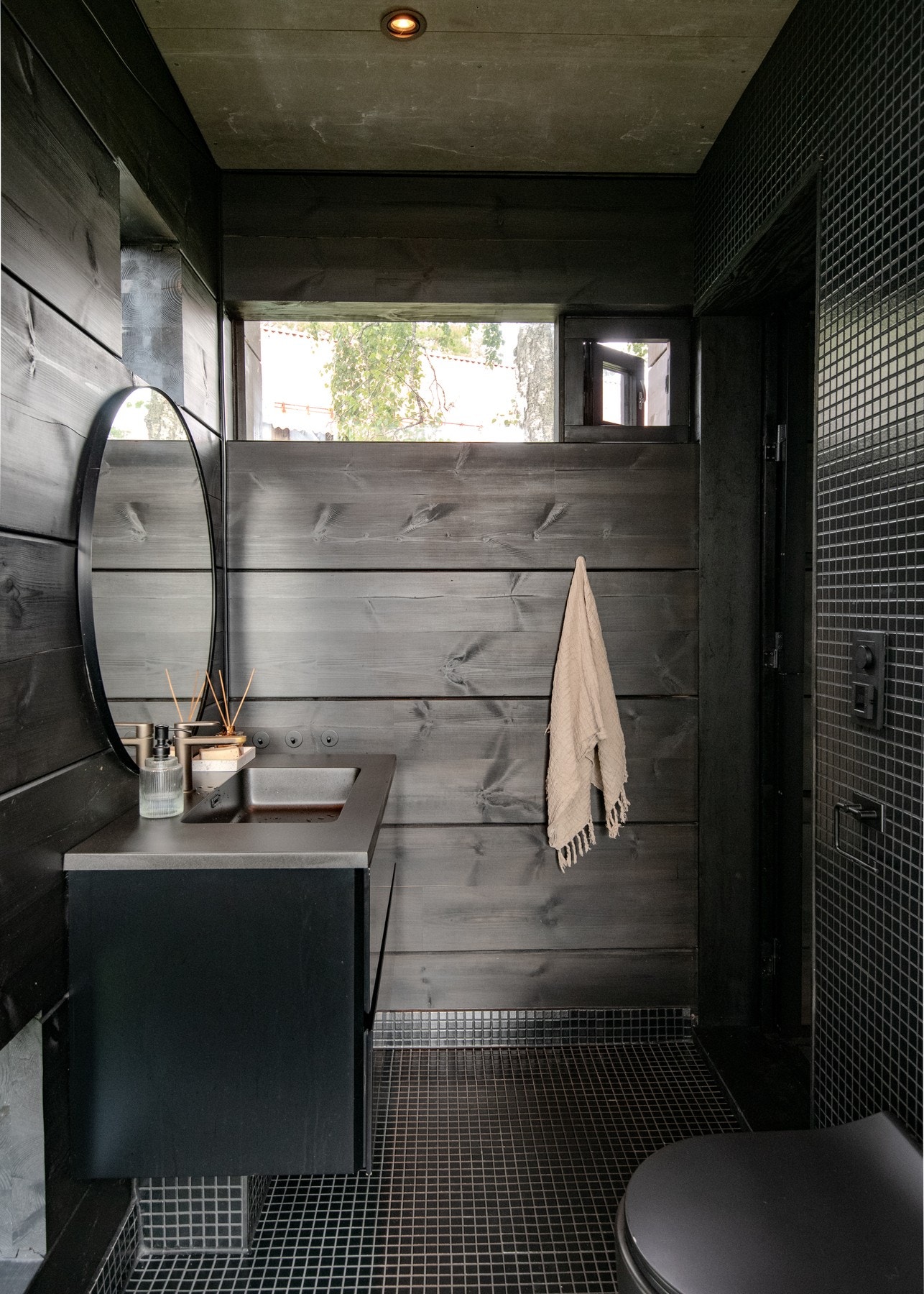 Badet har et eksklusivt materialuttrykk med fliser, glass og laftet tømmer. Galleribilde