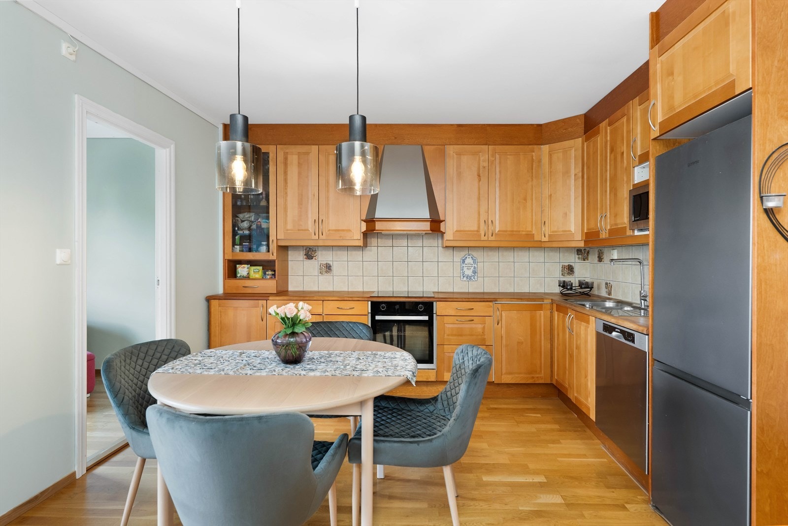 Kjøkken med heltre benkeplate og integrerte hvitevarer i en åpen løsning mot stuen. Galleribilde