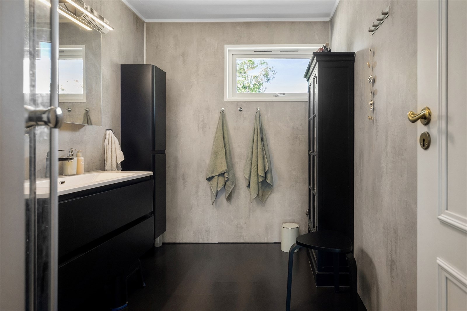 Badet er oppgradert med sort innredning og veggplater i betonglook. Galleribilde