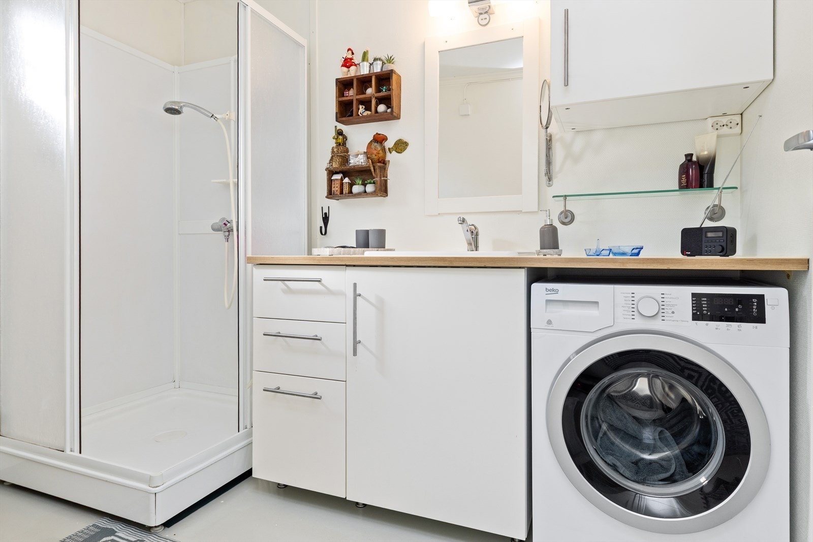 Bad med våtromsbelegg på gulv, baderomsplater i dusjsonen og opplegg for vaskemaskin. Galleribilde