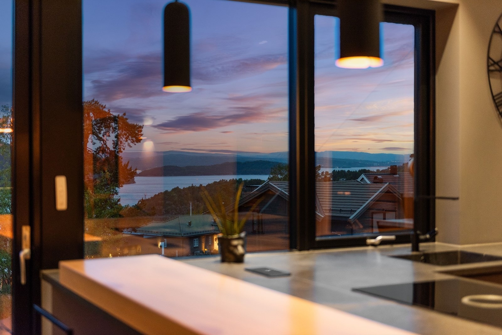 Kveldshimmelen speiler seg i fjorden utenfor. Galleribilde