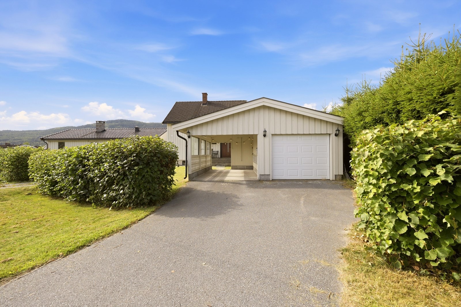 Eiet tomt med asfaltert adkomst i gårdsplass, romslig garasje m/carport, hage og terrasse Galleribilde