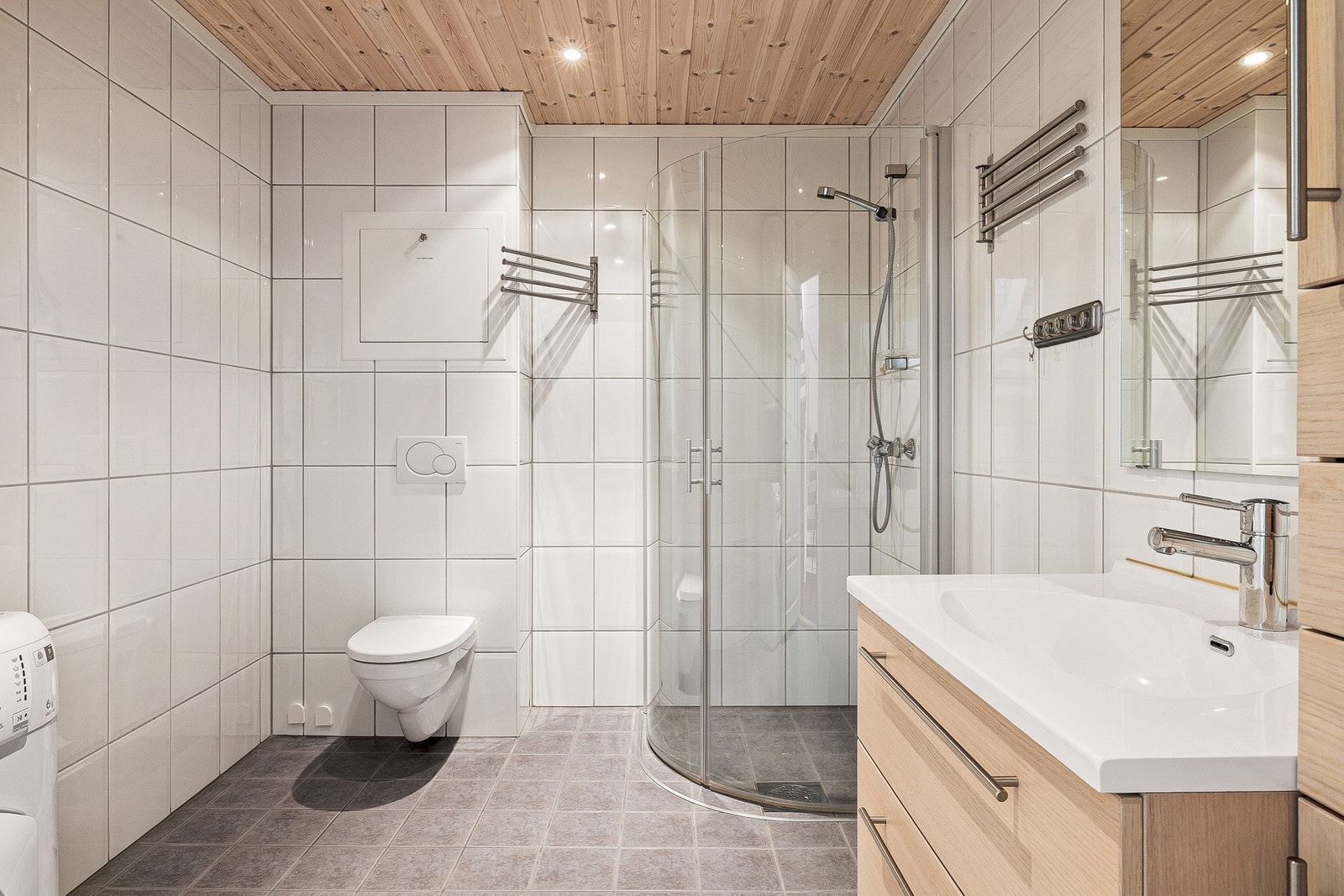 Badet fremstår stilrent med lune fliser og moderne baderomsinnredning Galleribilde