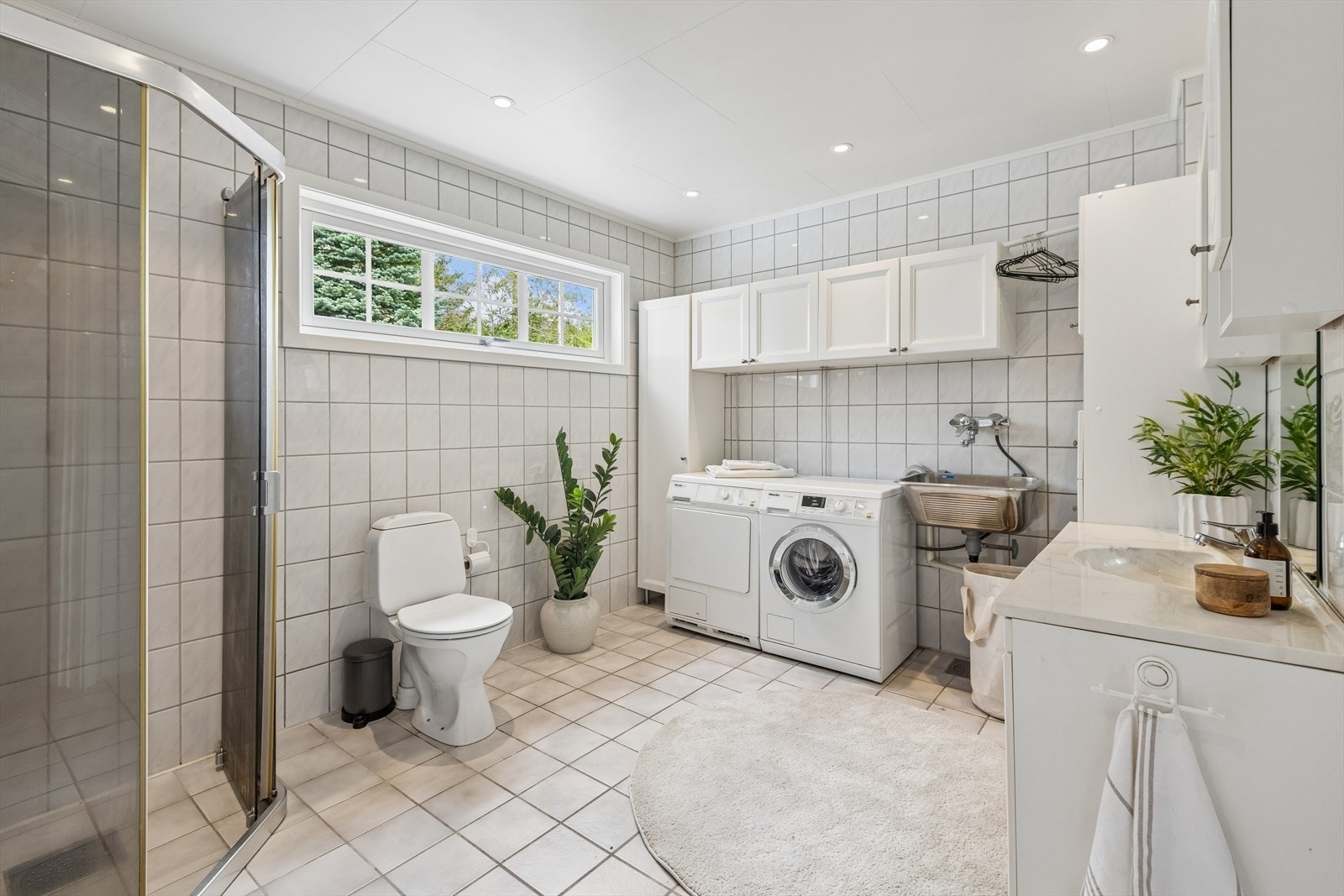 Lyst flislagt bad fra 1993. Badet er på 9 kvm og er benyttet delvis som vaskerom. Byttet vindu i 2026. Galleribilde