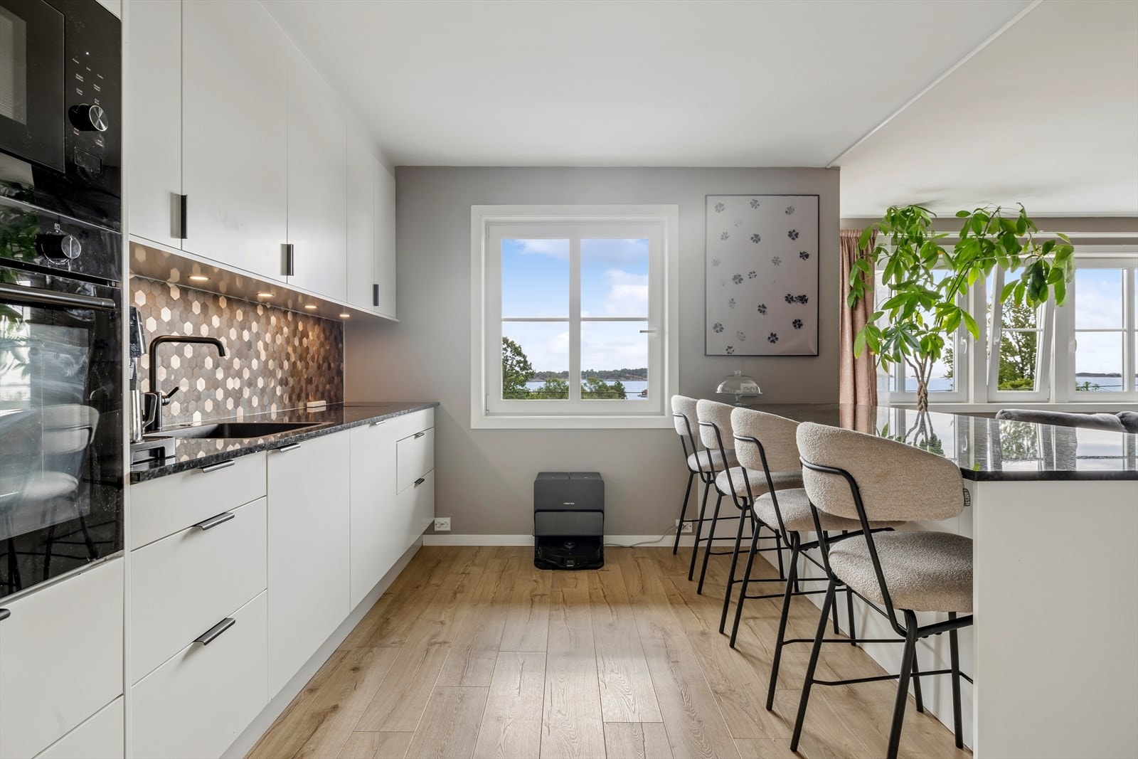 Stilfull hvit innredning og mørk benkeplate i stein. Galleribilde