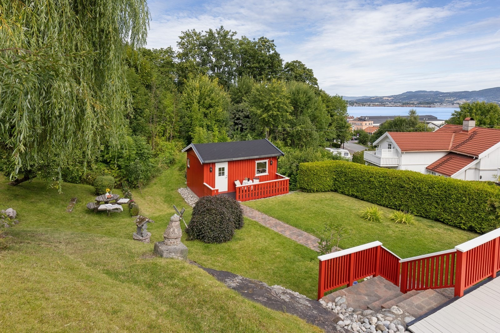 Stor, opparbeidet hage med uthus og utsikt mot fjorden. Galleribilde