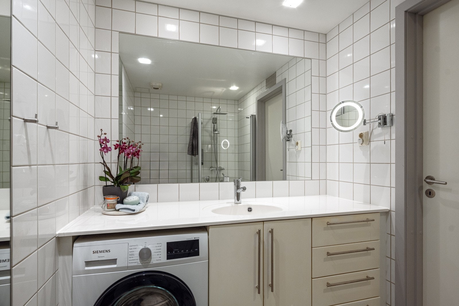 Badet er innredet med toalett, servant i helstøpt plate, dusj på gulv og opplegg for vaskemaskin. Galleribilde