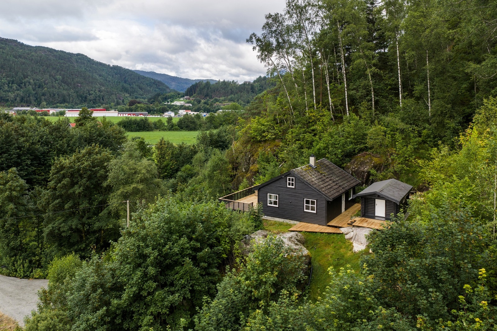 Bolig med naturskjønn beliggenhet, omkranset av frodig skog og med utsikt over dalen og nærliggende bebyggelse.