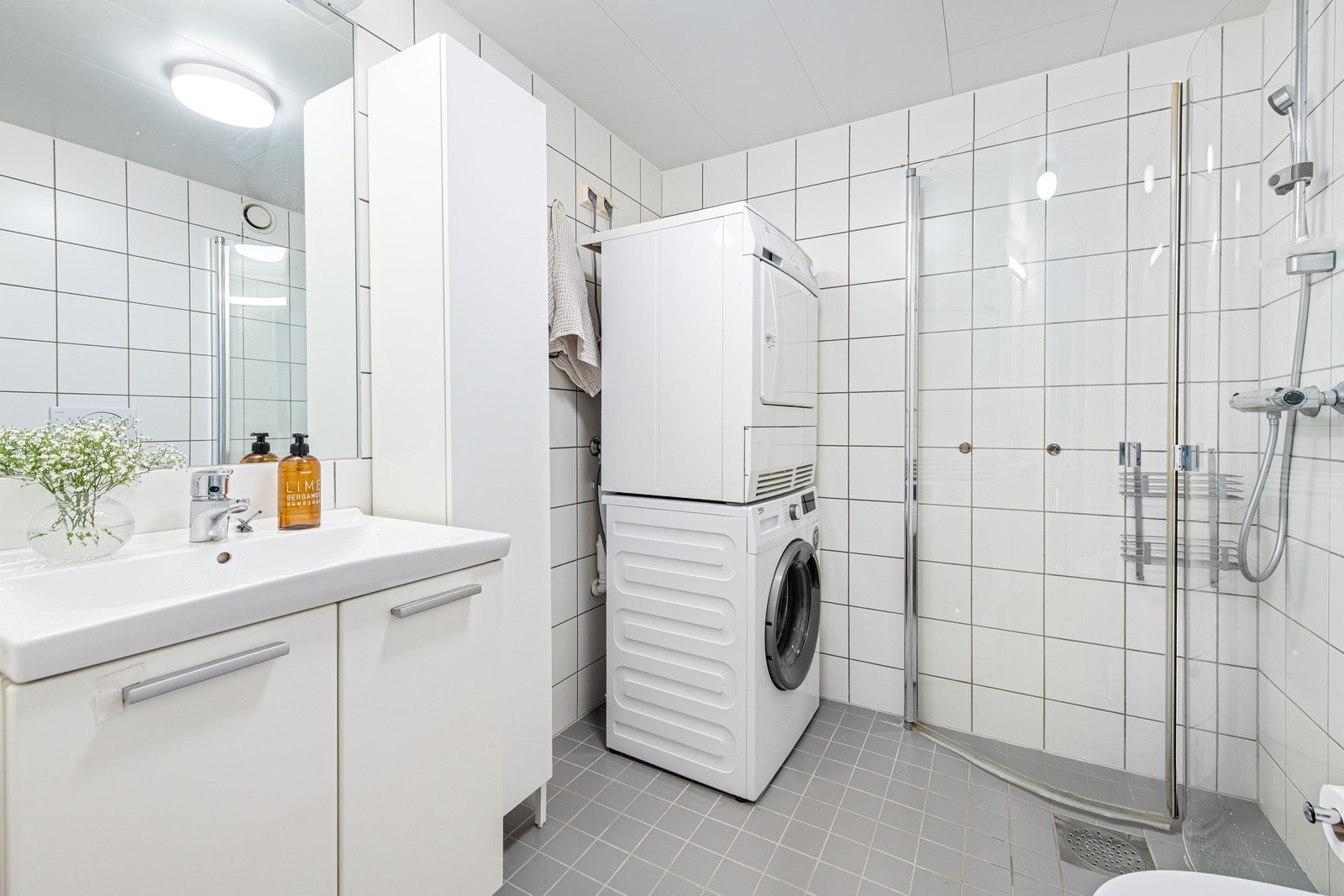 Badet har flislagte vegger og gulv med vannbåren varme, samt opplegg for vaskemaskin og tørketrommel Galleribilde