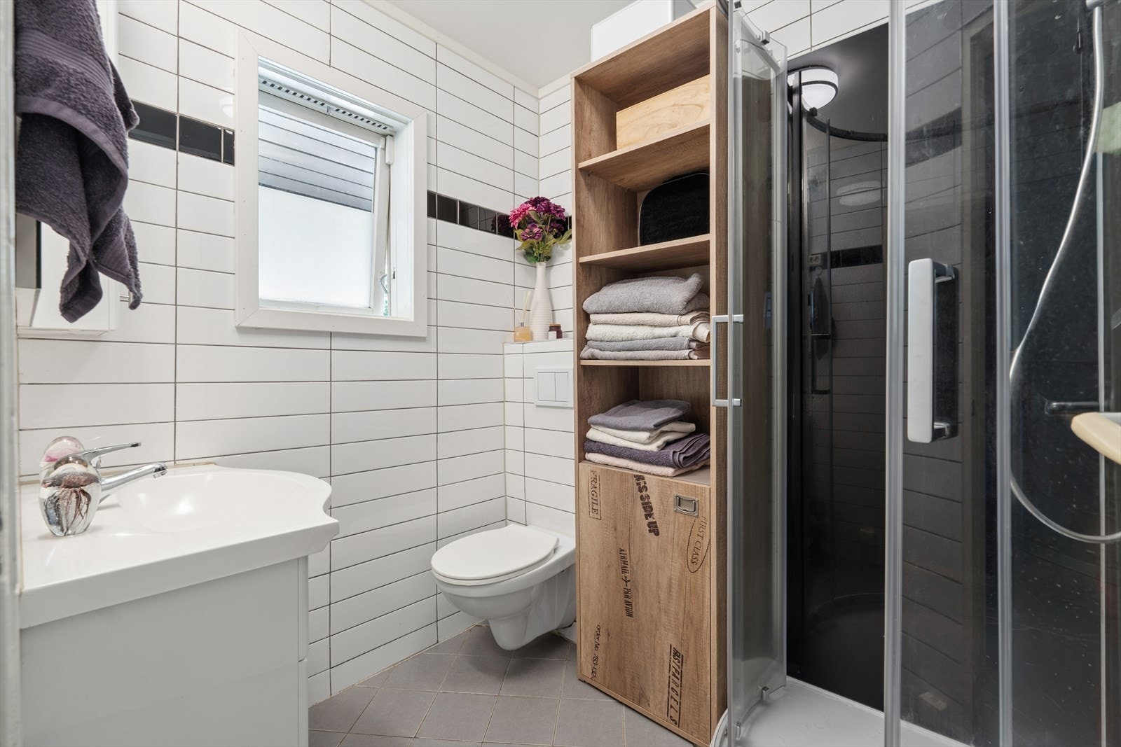 Våtrommet er innredet med nedfelt servant, veggmontert toalett og dusjkabinett. Badet har flislagt gulv med elektriske varmekabler. Galleribilde