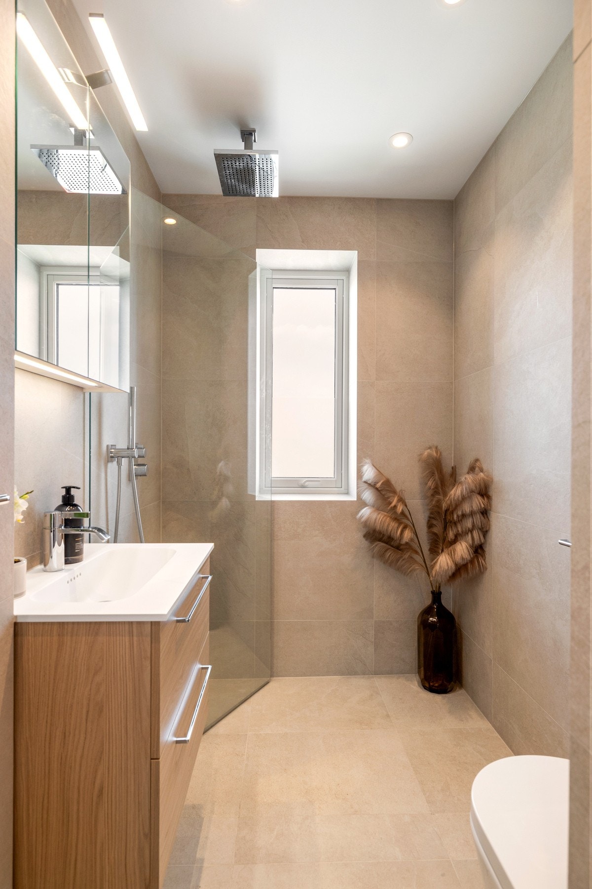 Badet har store, delikate fliser på gulv og vegger, behagelig gulvvarme og downlights i himling Galleribilde