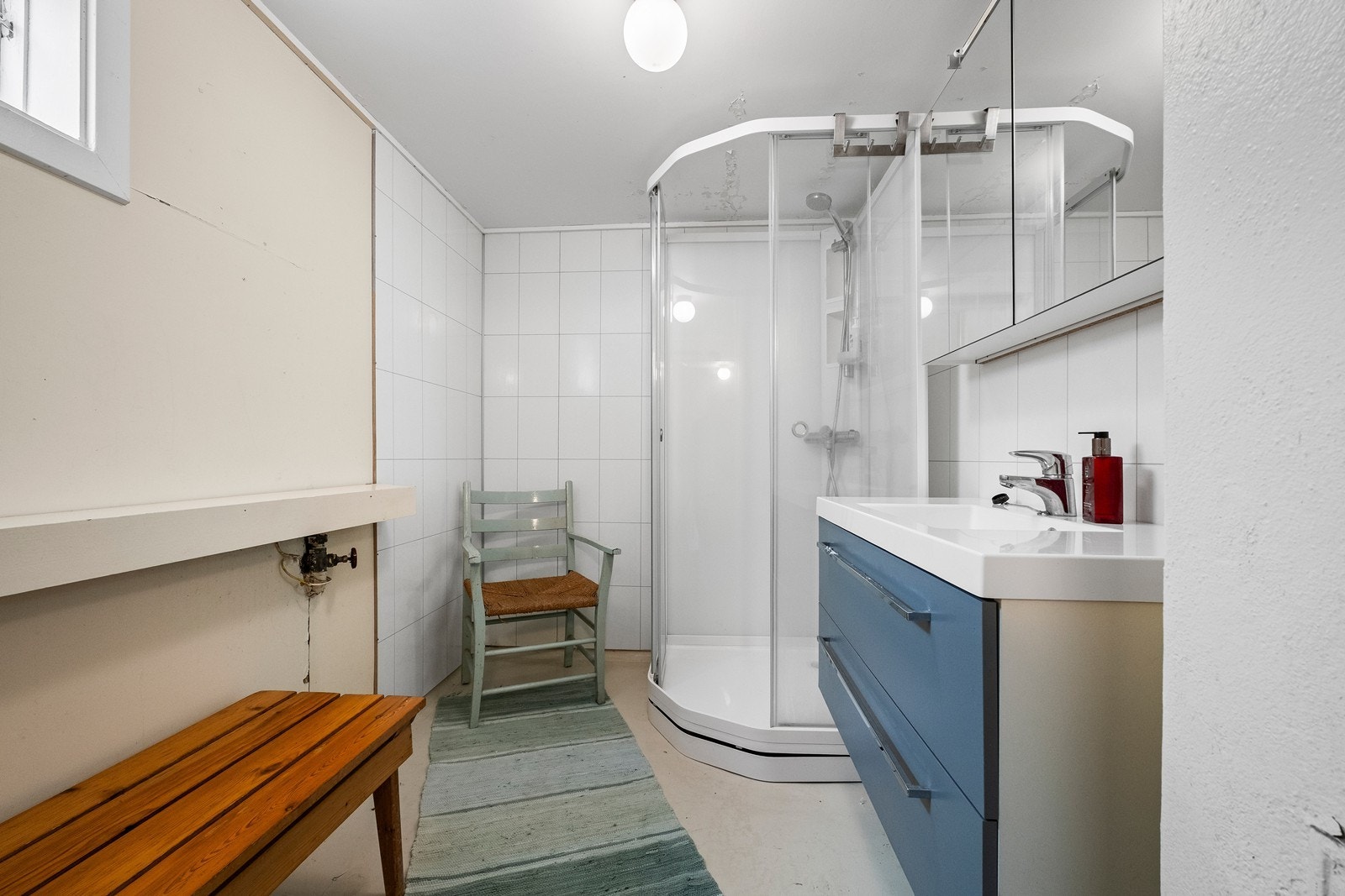 Bad utstyrt med dusjkabinett, servant med underskap og speilskap. Galleribilde