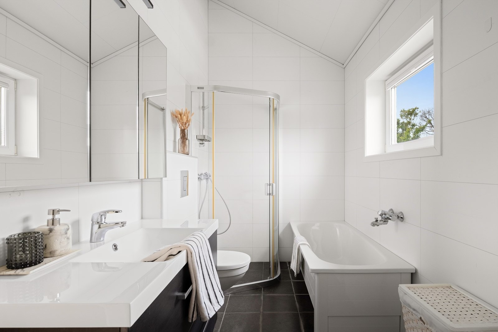 Badet har en moderne og praktisk utforming, og er utstyrt med servant, badekar og dusjhjørne. Galleribilde