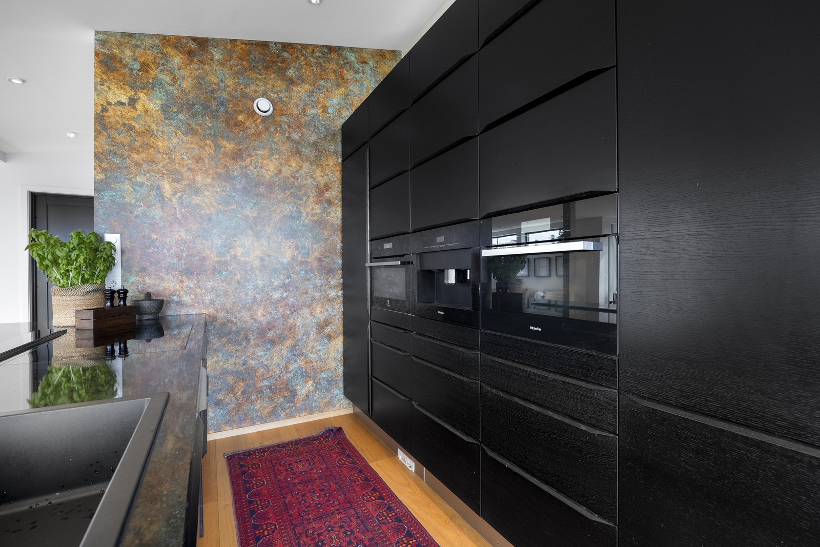 Kjøkkenet er utstyrt med integrerte hvitevarer fra Miele som sikrer et helhetlig design. Stekeovn, kombi steke/dampovn, samt integrert kaffemaskin kan sees i høyskap. Galleribilde