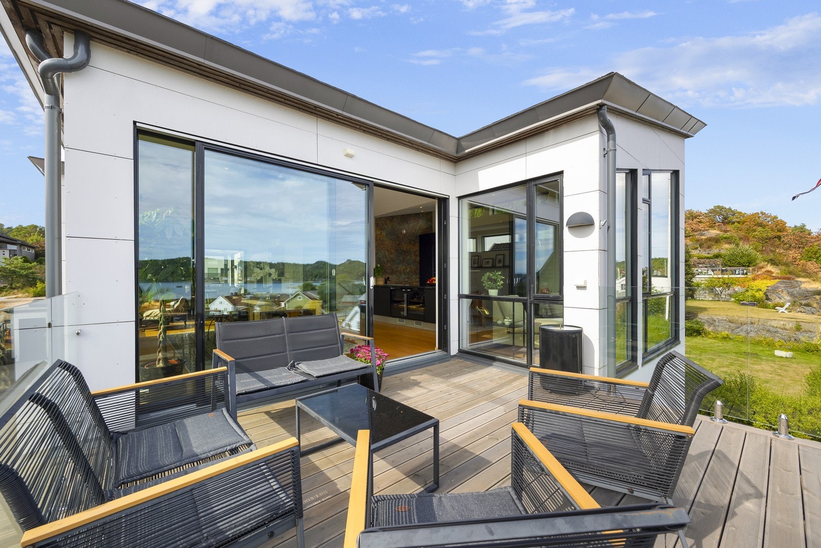 Direkte utgang fra oppholdsområdet til en moderne terrasse med glassrekkverk. Galleribilde
