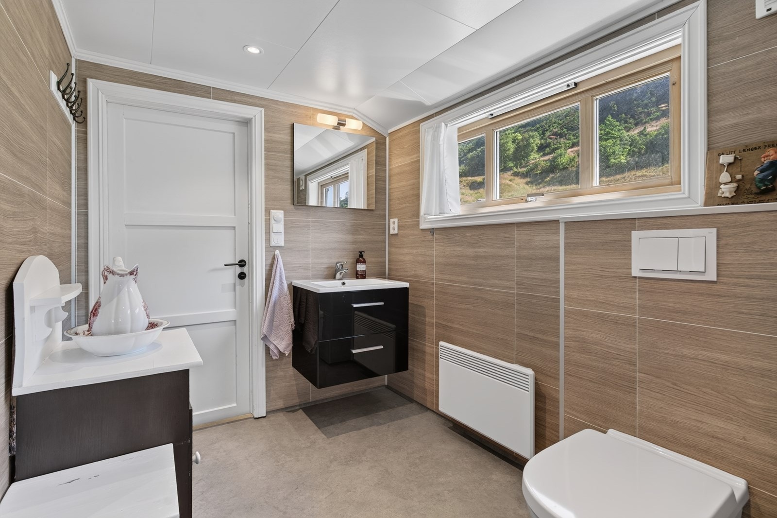 Badet i loftsetasjen har innredningen som består av underskap med oppbevaring, vask med speil, vegghengt toalett og dusjvegger Galleribilde
