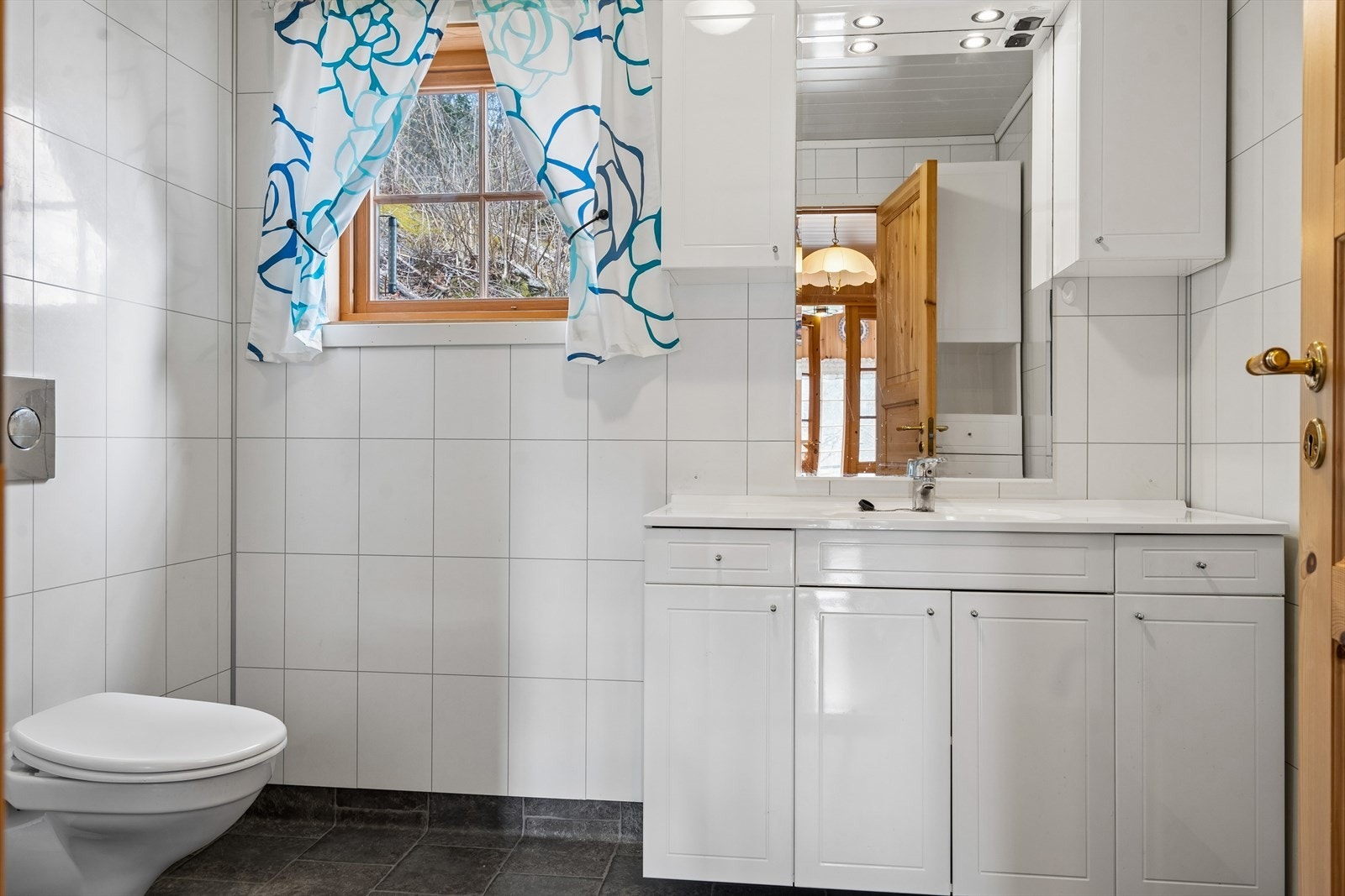 Badet er innredet med vegghengt toalett, innfellbare dusjdører, servant m/innredning og speil. Galleribilde