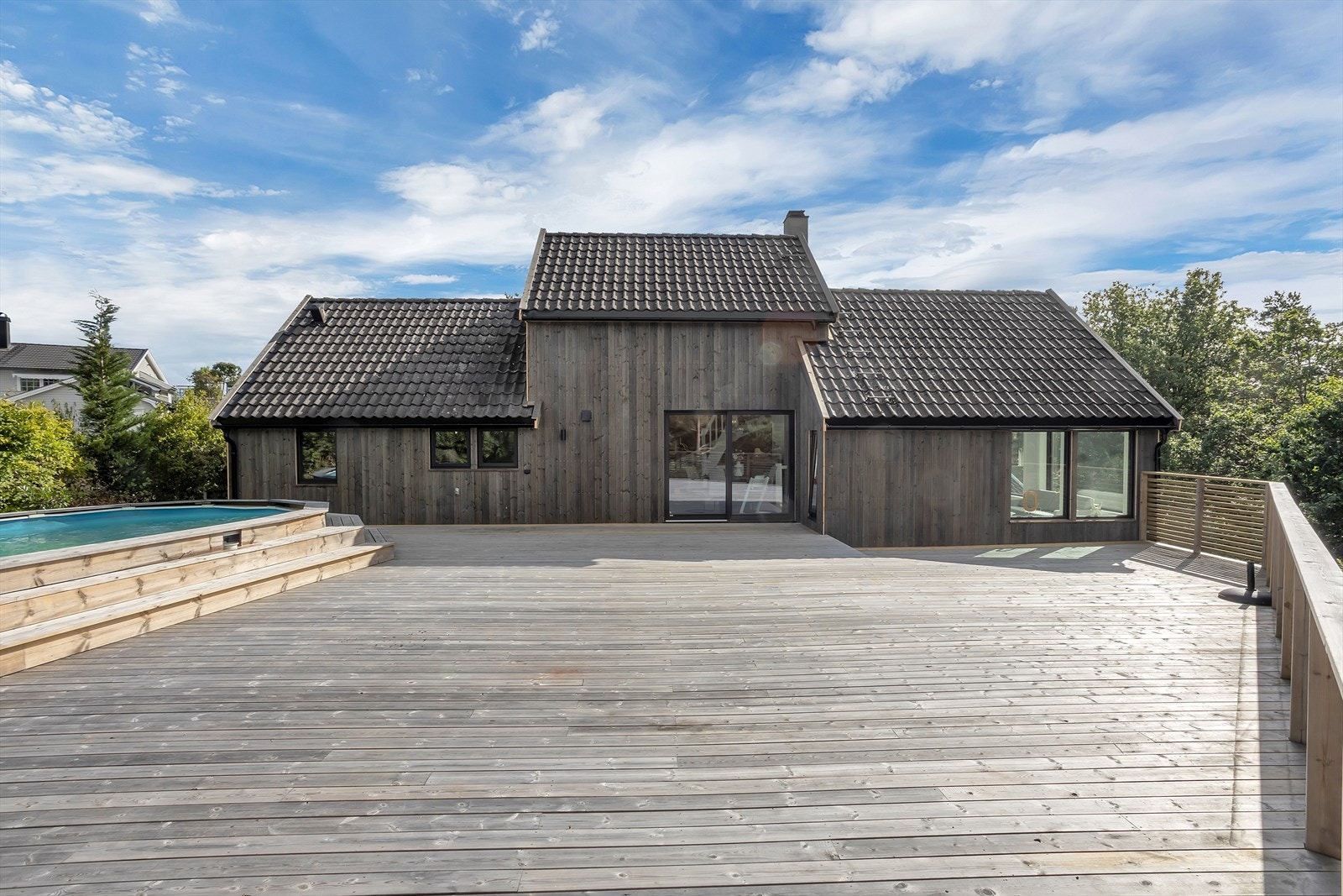 På baksiden av eiendommen venter et stort og innbydende terrasseområde med basseng, god plass til flere sittegrupper og en skjermet beliggenhet omgitt av grøntareal. Galleribilde