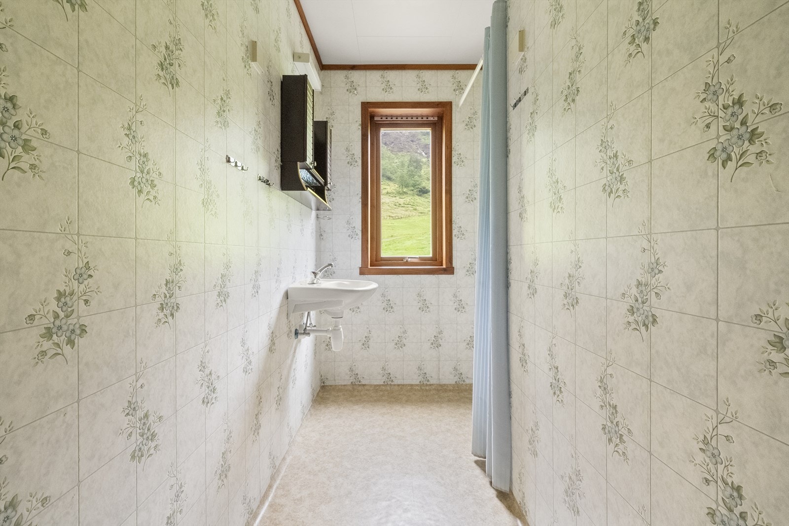 Badet i 1. etasje har dusj med forheng og veggmontert servant. Galleribilde