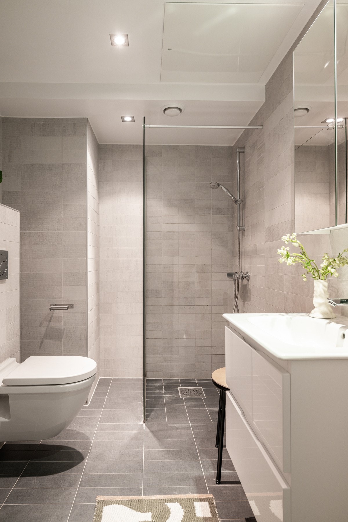 Badet er innredet med servant med innredning, speil, dusjhjørne med glassvegg, vegghengt toalett Galleribilde
