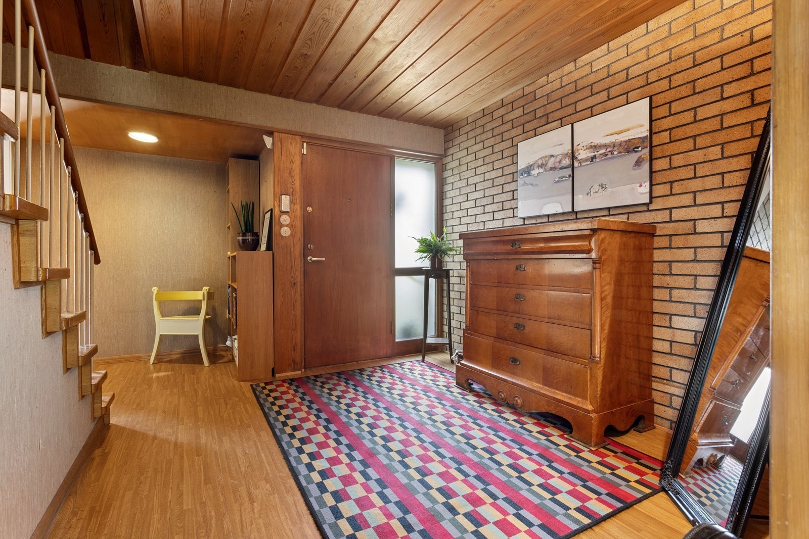 Her blir du ønsket velkommen inn via en romslig entré med teglstein på den ene veggen og panelt tretak, detaljer som umiddelbart formidler husets arkitektoniske identitet. Galleribilde