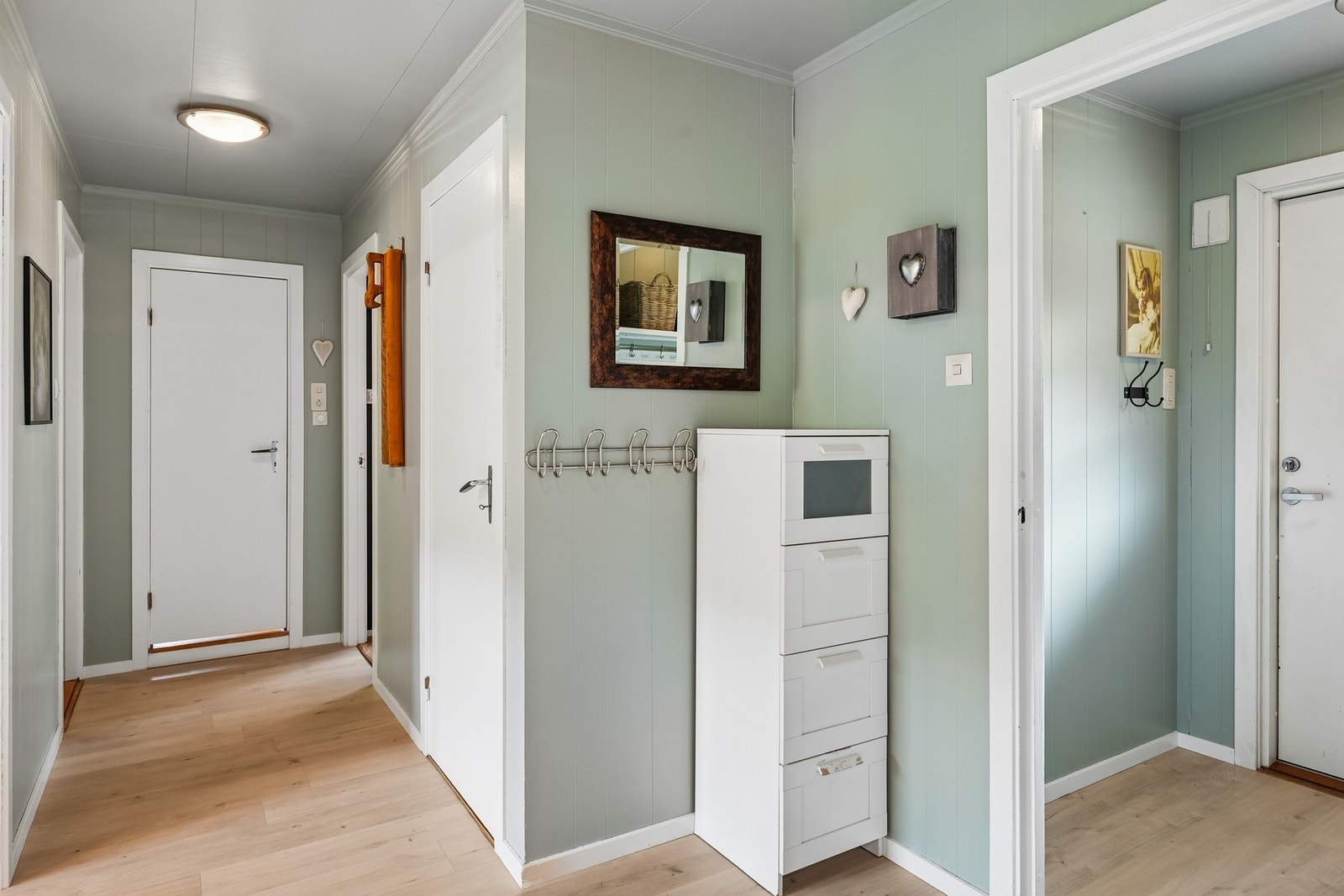 Entré og gang. Gulvet er laminat, malt panel på vegger samt plater i himling. Her er noe knagger på vegg til oppheng av tøy samt noe plass til garderobemøblement. Galleribilde