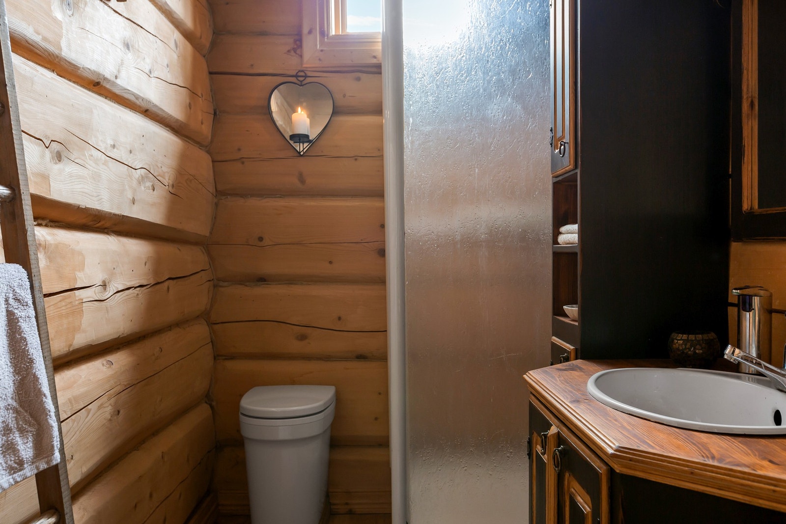 Badet har tømmervegger og tregulv, og er innredet med dusjkabinett og gulvmontert urinal. Galleribilde