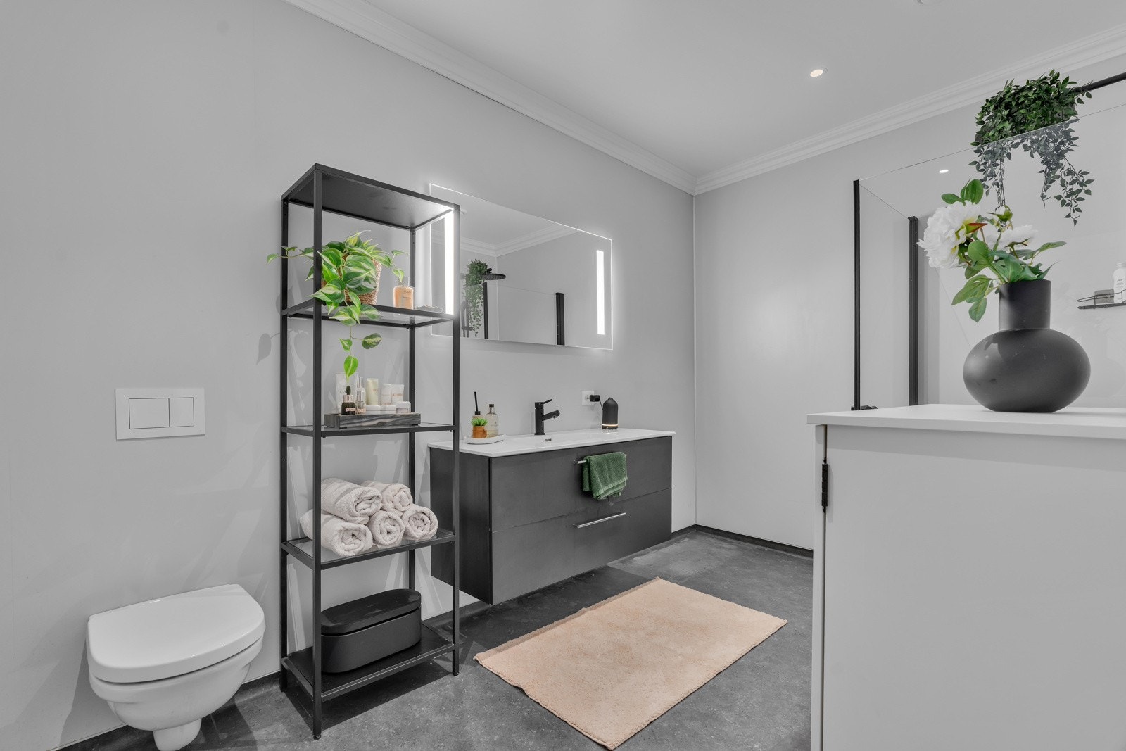 Badet har lys i speil og sort innredning med hvit vask. Galleribilde