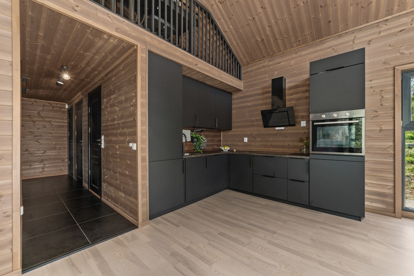 Kjøkkenet ligger i åpen løsning mot stue og spisestue. Innredningen har et moderne, stilrent uttrykk med slette, mørke fronter og mørk benkeplate i laminat. Galleribilde