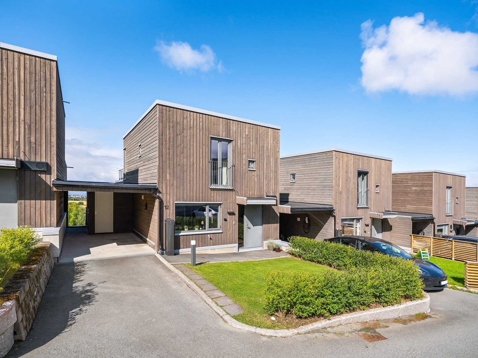 Eiendommen har et pent opparbeidet inngangsparti med carport, ladepunkt for elbil, oppstillingsplass og en sportsbod på ca. 5 kvm. Galleribilde