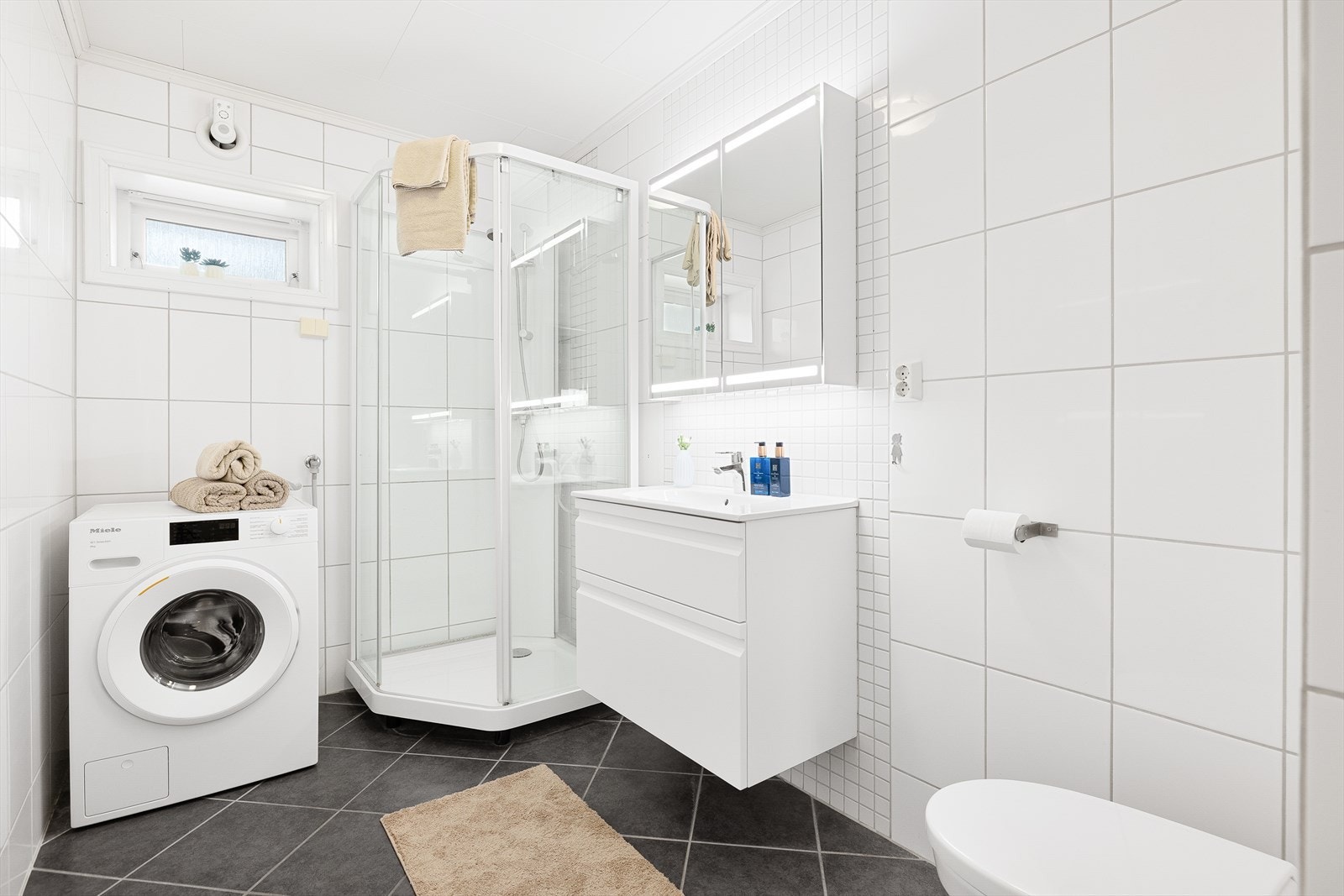 Badet i 1. etasje er flislagt fra topp til tå, og har opplegg for vaskemaskin, servant i skap, og veggmontert toalett. Baderommet ble pusset opp i 2007 av faglært murer og rørlegger. Galleribilde