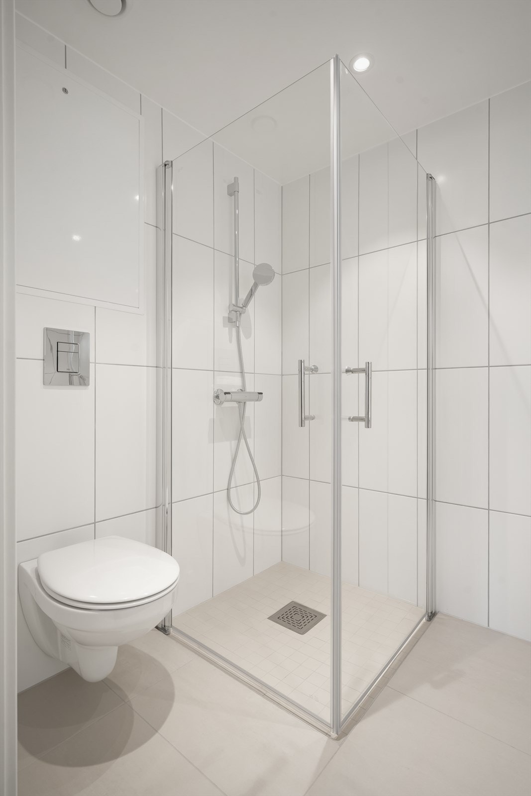Bad/vaskerom med fliser i store formater og downlights Galleribilde