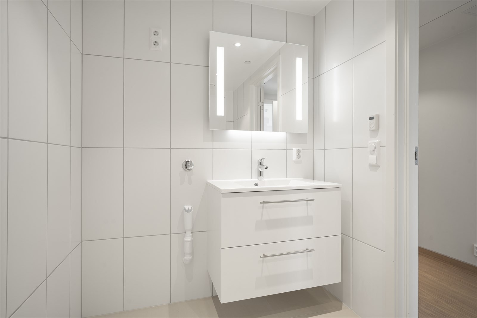 Bad/vaskerom med fliser i store formater og downlights Galleribilde