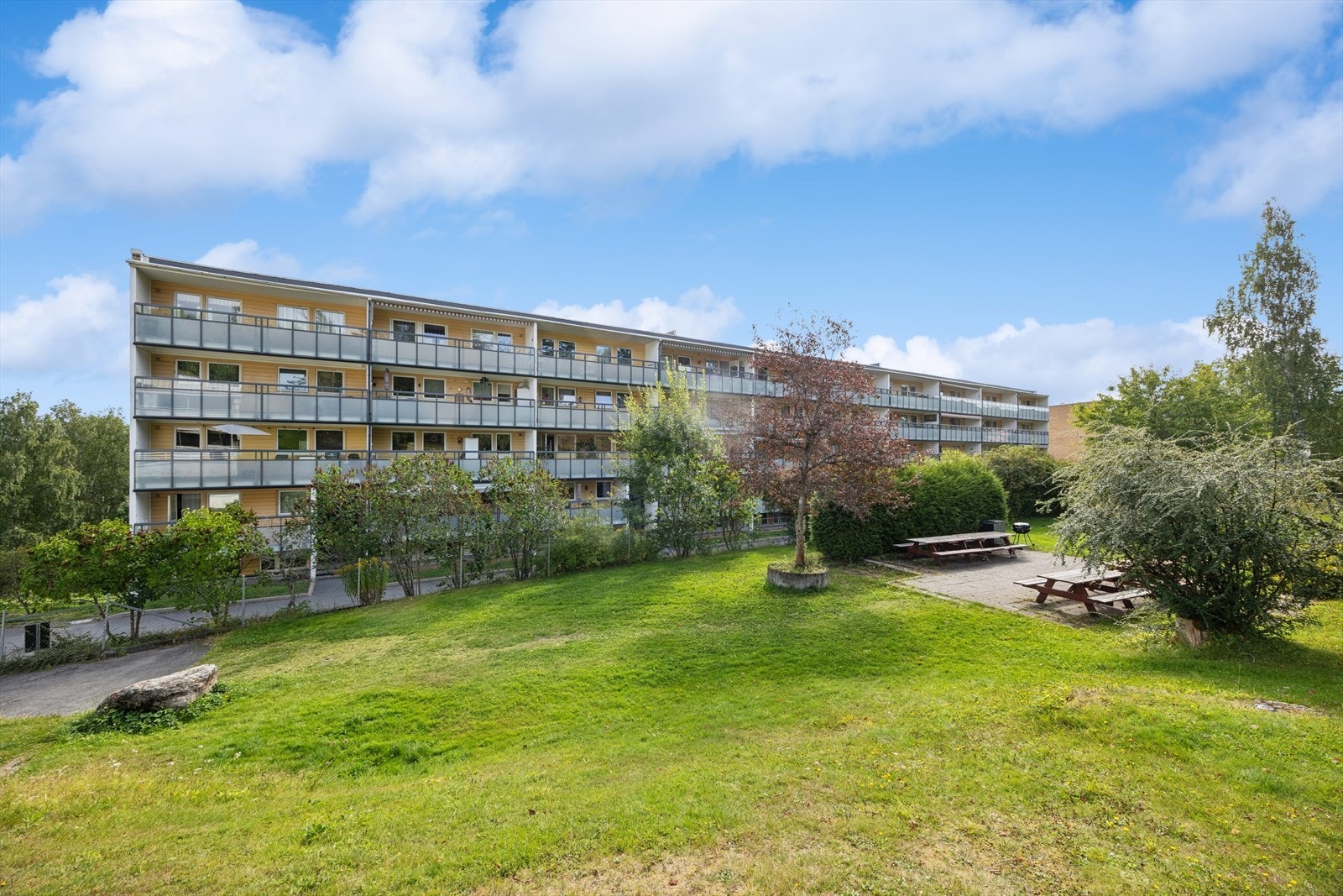 Pent opparbeidede fellesarealer med plen, beplantning, sittegrupper og lekeplass. Galleribilde