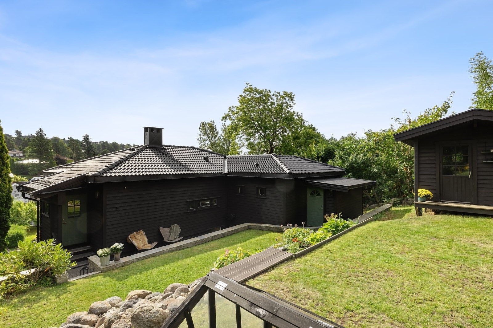 Tomten er pent opparbeidet og byr på et variert uteområde med gressplen, beplantede bed, naturstein og granittbelagte partier Galleribilde