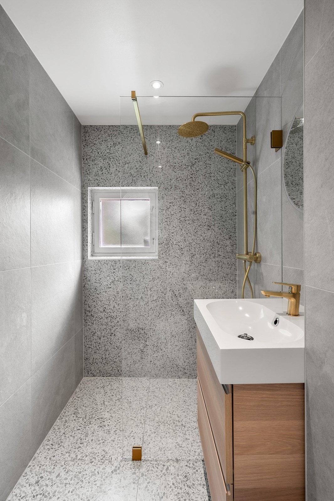 Badet er innredet med vegghengt toalett og dusjhjørne med fast glassvegg og regnfallsdusj. Gjennomgående lekre detaljer i børstet messing Galleribilde