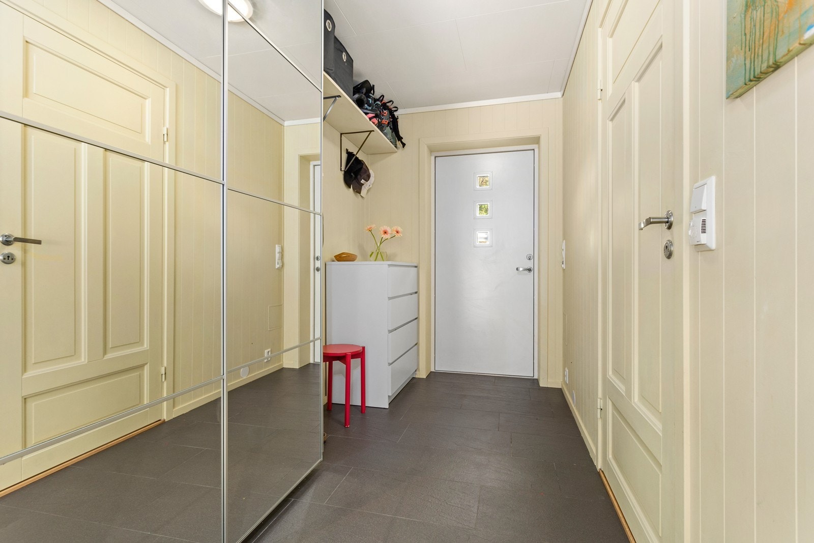 Flislagt entré med stor skyvedørsgarderobe og plass til oppbevaringsløysing for ytterklede og sko. Galleribilde
