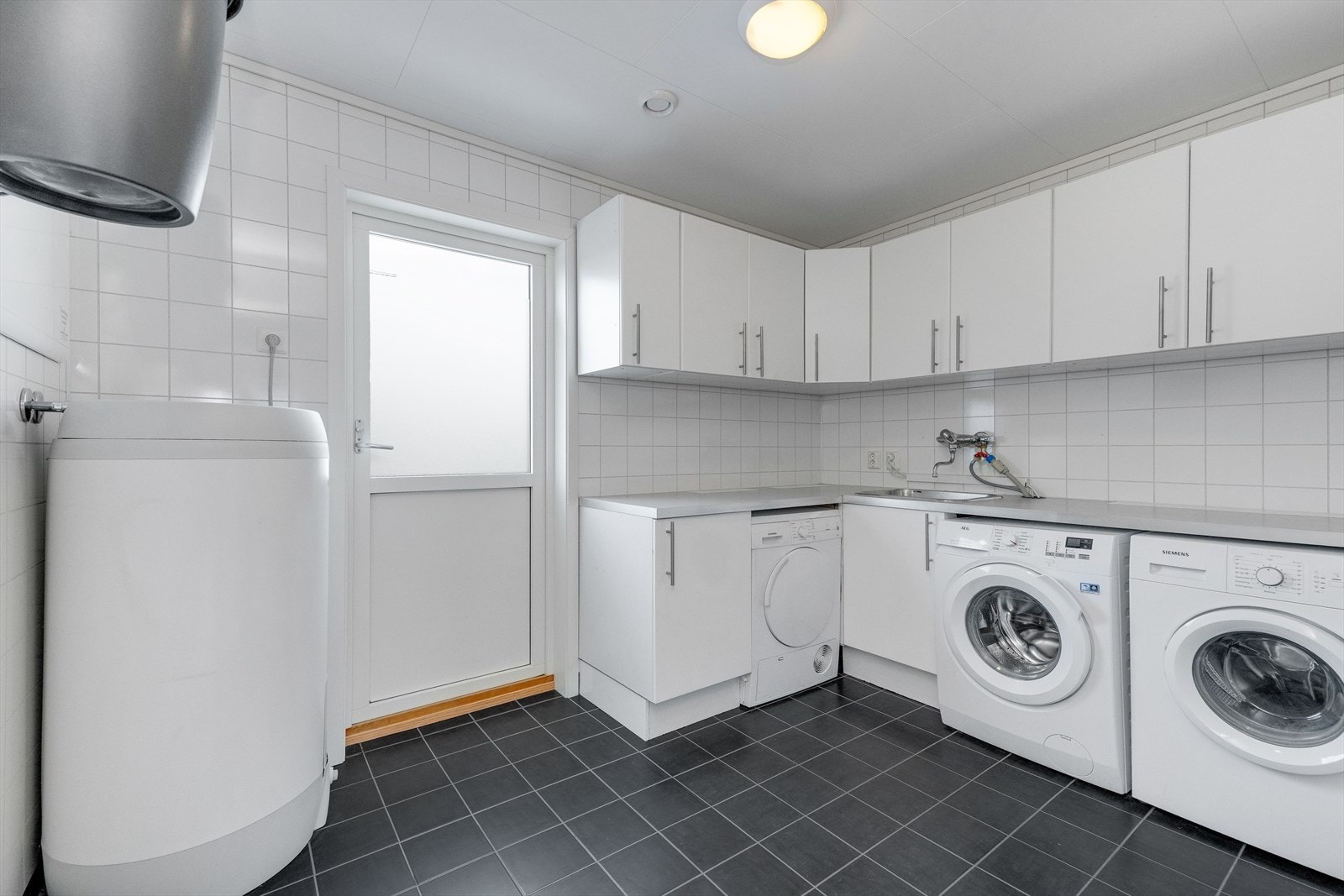 Stort og flott vaskerom med inngang fra uteområdet. Godt med oppbevaringsplass i rommets innredning. Inngang til teknisk rom/lagerrom fra vaskerommet. Galleribilde