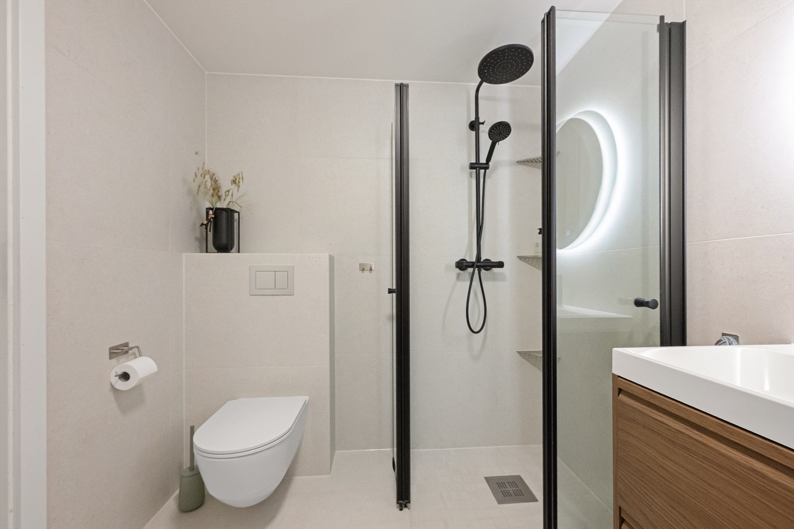 Badet har vegghengt toalett og et nedsenket dusjhjørne med innfellbare glassvegger. Galleribilde